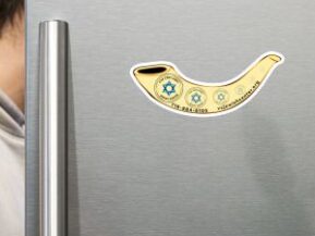 Man opening fridge with shofar-shaped magnet featuring the Van Cortlandt Jewish Center logo.
