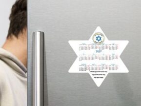 Person opening a refrigerator with star-shaped calendar magnet