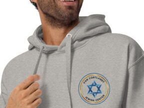 Man smiling in gray hoodie with Van Cortlandt Jewish Center logo